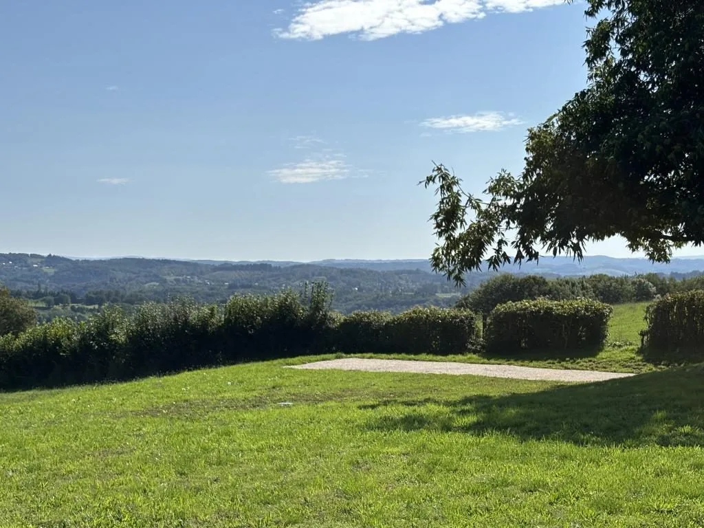 La piscine en eau et la dépendance en pierre, sous un ciel bleu